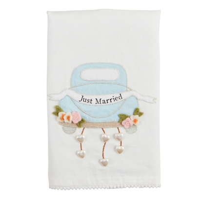 The Wedding Beaded Tea Towel is a white cotton hand towel featuring a premium appliqué of a blue car with "Just Married," adorned with flowers and heart charms. Available in standard size.