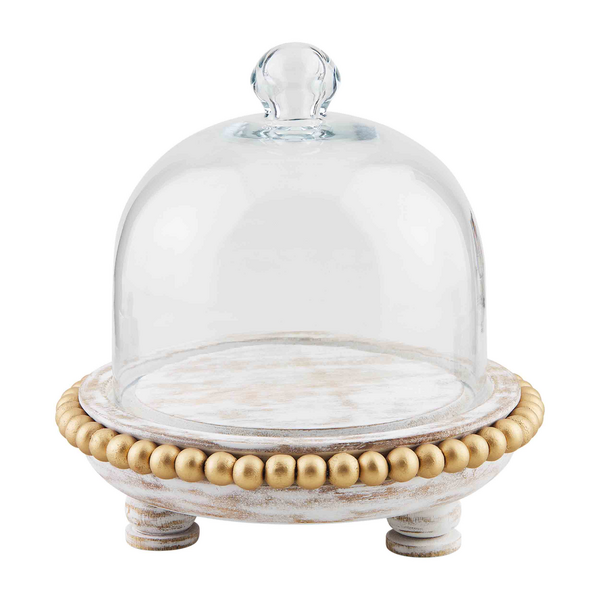 Small round gold glass cloche cake stand with whitewashed mango wood base, gold beads, and clear cloche. Available in one size.