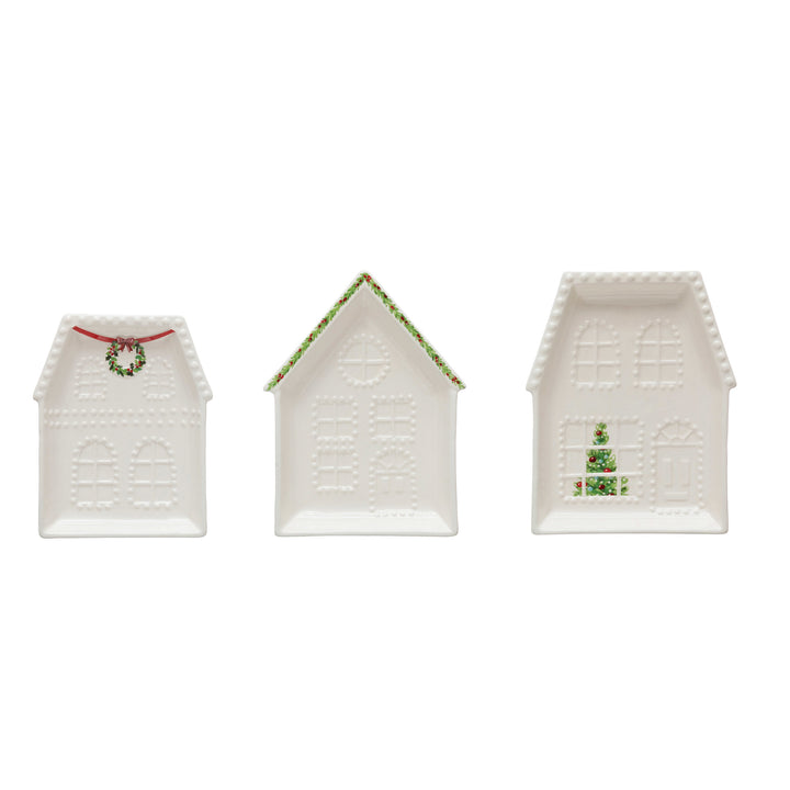 Three embossed stoneware house plates featuring wreath, garlanded roof, and Christmas tree designs.
