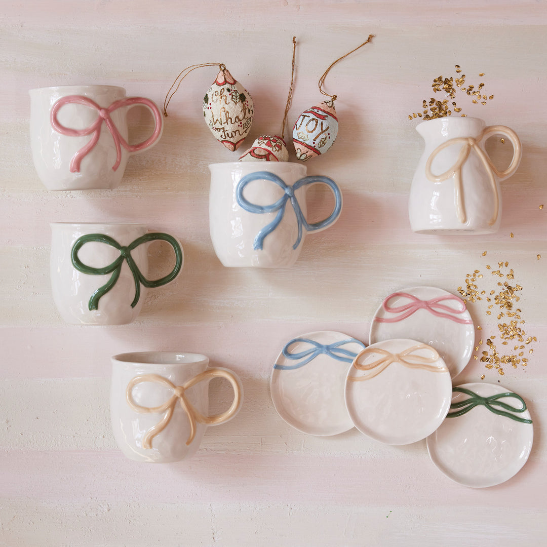 Handcrafted pastel ceramic mugs and plates with raised ribbon and bow accents. Available in multiple sizes.