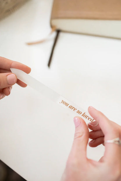 Translucent salon-quality glass nail file with gold 'you are so loved' text; available in standard and travel sizes.