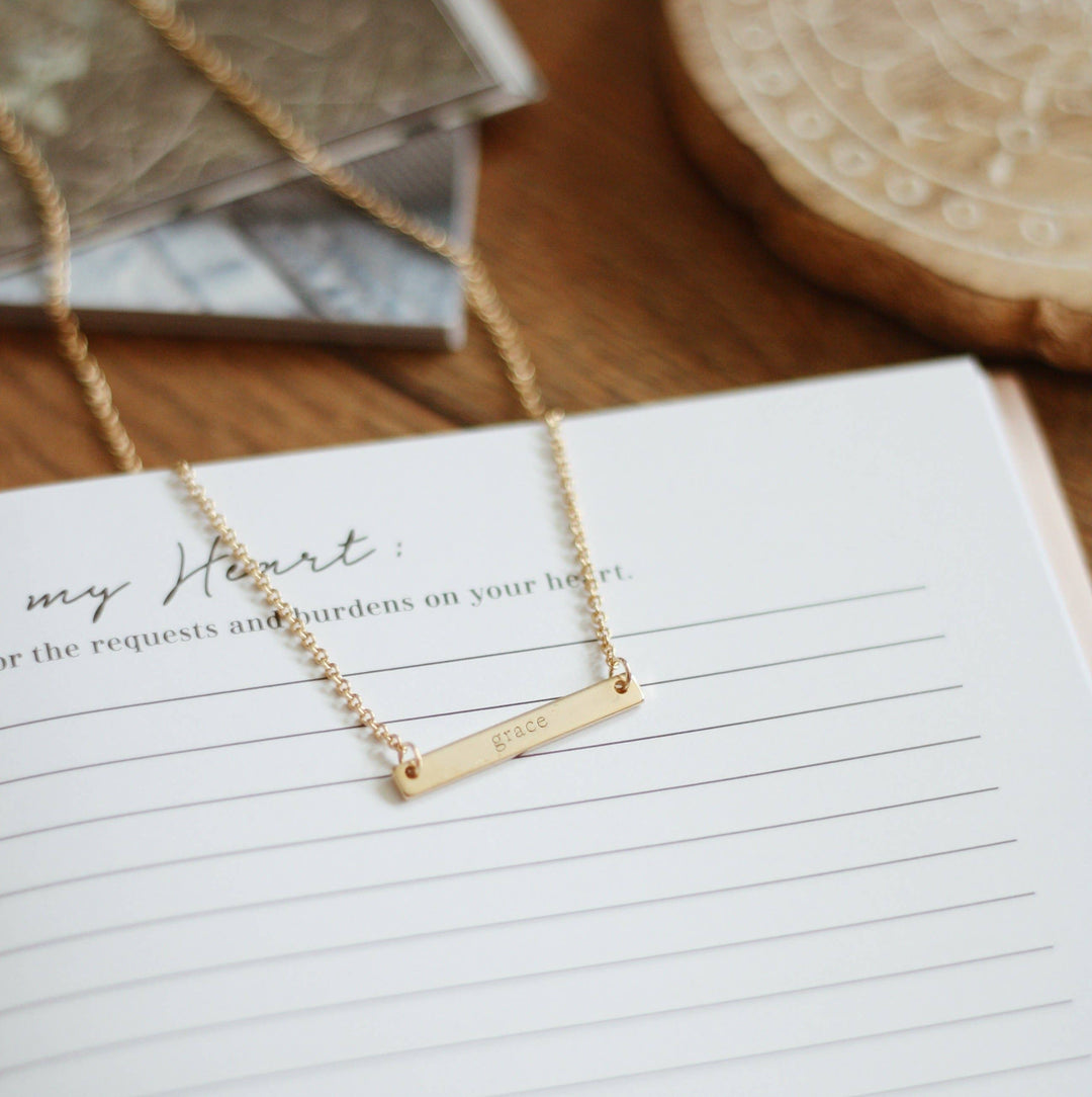 The Grace Necklace: 18k gold plated bar engraved with "grace," adjustable, fits 16-18 inches.