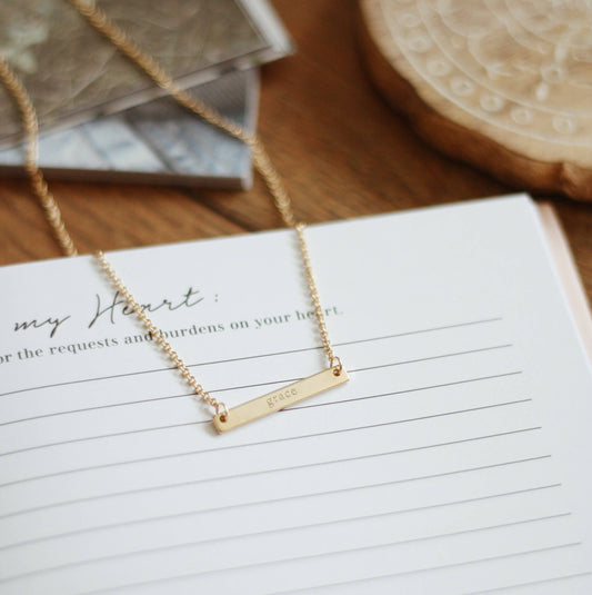 The Grace Necklace: 18k gold plated bar engraved with "grace," adjustable, fits 16-18 inches.