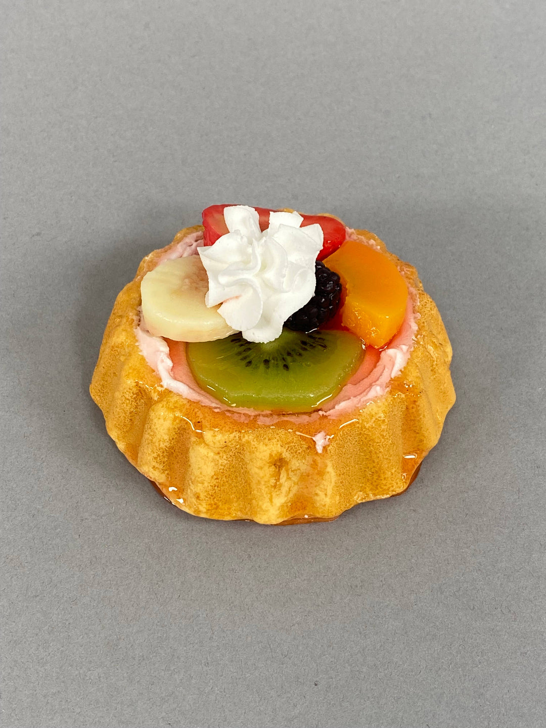 Small Fake Assorted Fruit Tart with golden pastry, faux kiwi, banana, strawberry, peach, blackberry, whipped cream. Sizes: small.