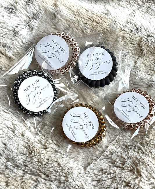 25-pack of individually wrapped hair coils in leopard print and solid colors with "Thank You!" labels. Sizes: assorted.