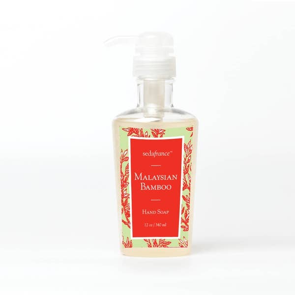 This product is a clear bottle of 'Malaysian Bamboo Liquid Hand Soap'. It features a convenient pump dispenser for ease of use. The bottle is adorned with an attractive floral pattern in red and green tones, making it a stylish addition to any bathroom or kitchen decor. The soap inside gives off the exotic scent of Malaysian Bamboo, turning handwashing into a more luxurious experience. This liquid hand soap comes in one size: the standard 12 fluid ounces format.