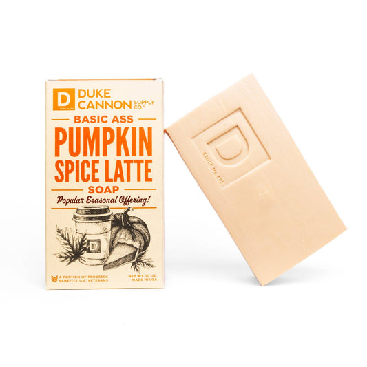 A bar of Basic Ass Pumpkin Spice Latte Soap alongside its packaging, which features vintage style lettering and autumnal bliss illustrations. the soap has an embossed "d" on it.