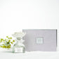 The Sunshine Rose Ceramic Flower Diffuser Gift Set - Serenity includes a glass bottle with ceramic flower cap; available in various sizes.