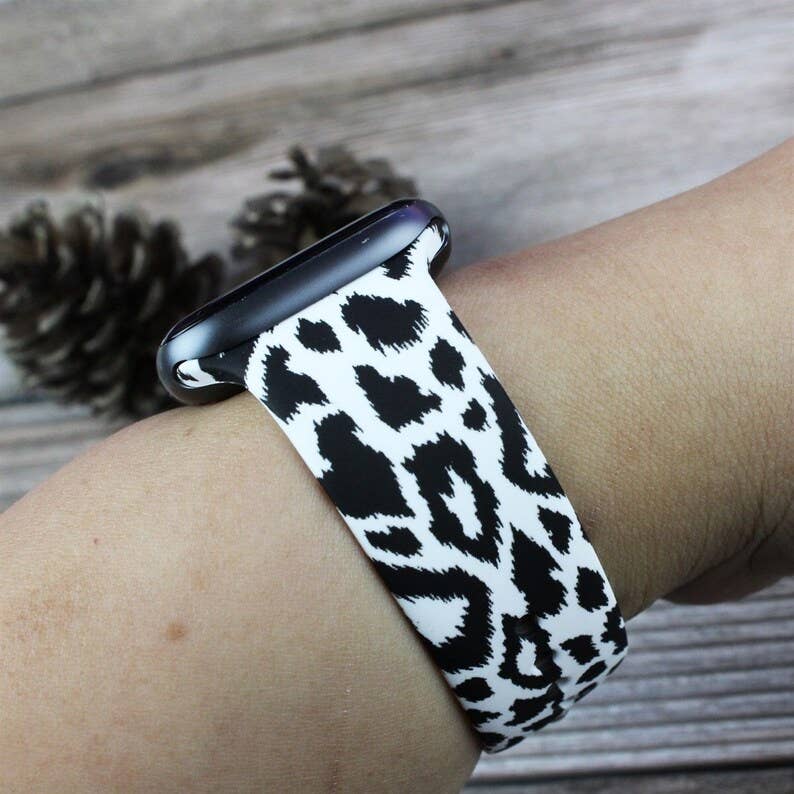 This product is an Apple Watch featuring an Animal Themed Printed Silicone Bands in a vibrant black and white cow print. Made of silicone, this watch band is robust and durable, designed for a long-term use. The product can be adjusted to fit various wrist sizes and is compatible with all series of Apple Watches.