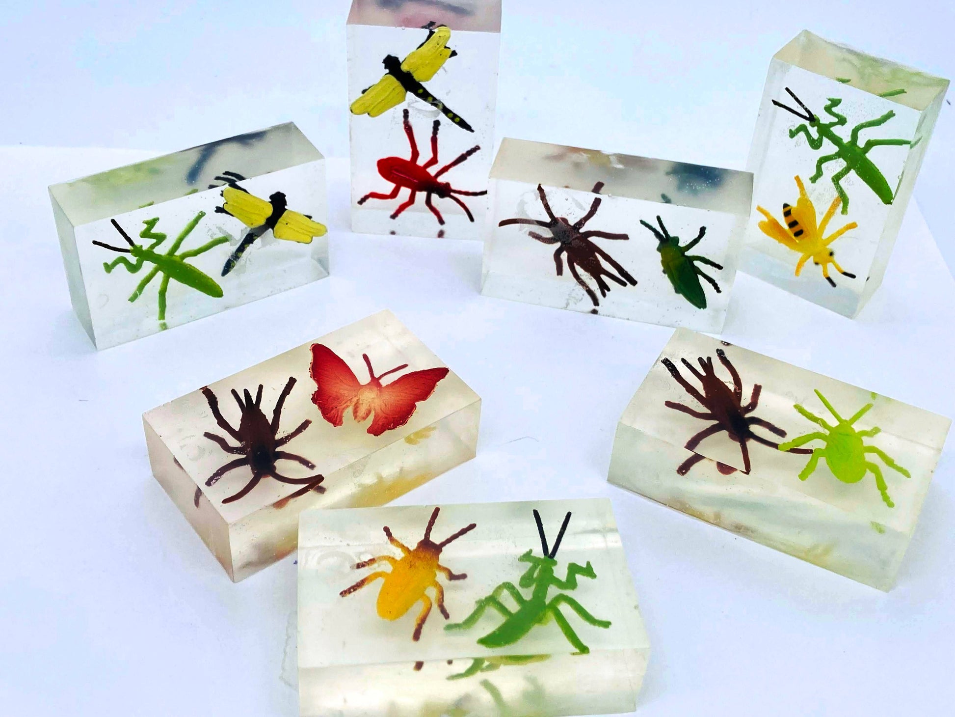 The Grab 'n Go Minis, from the Bugs In Your Soap Collection, feature brightly colored, realistic insect specimens showcased against a pristine white background. Each soap is sold individually.