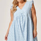 White Eyelet Babydoll Dress with v-neckline and ruffled shoulders. Available in sizes XS–XL.