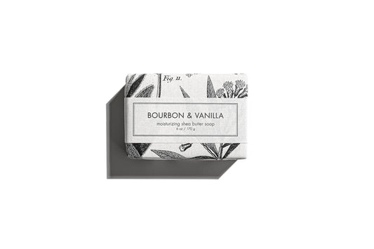 The product is a bath bar of Bourbon & Vanilla Soap. This soap comes in an aesthetically pleasing black and white packaging, adorned with elegant botanical illustrations. It is displayed isolated on a white background, suggesting its pure and clean attributes. The size of the soap bar is not specified in this description.