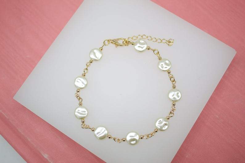 An 18K gold filled bracelet adorned with heart-shaped pearl charms. Available in various sizes.