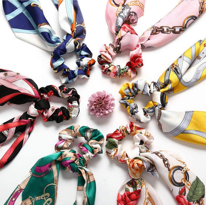 Seven vintage floral scarf scrunchies with vibrant patterns and scarf-like tails. Available in one-size fits all.