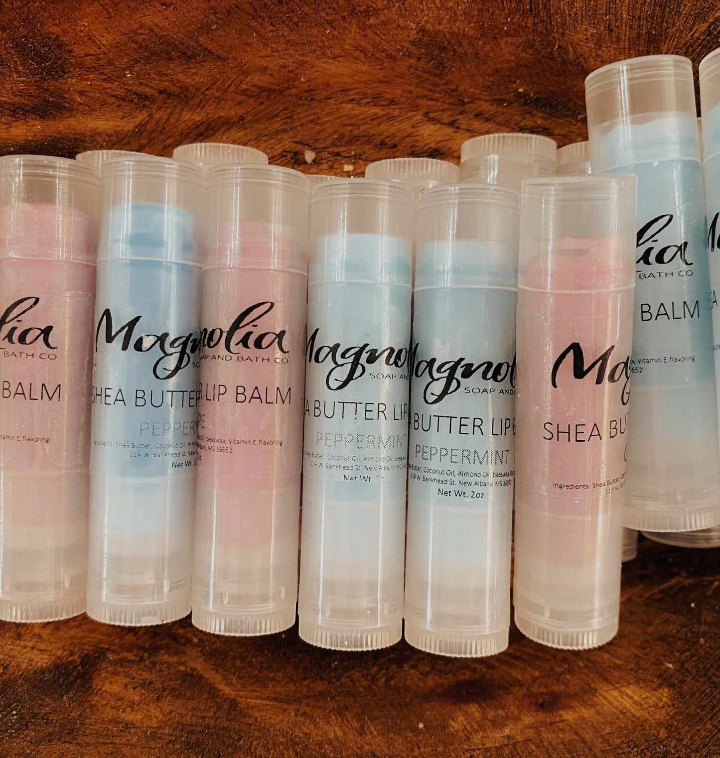 This product is a collection of cylindrical Lip Balm tubes with "Magnolia" branding. The lip balms comprise all-natural shea butter. They are showcased in various shades of pink and blue. Available in one standard size.