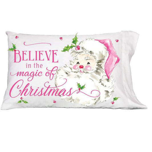 Believe In The Magic Of Christmas Pillowcase": Standard-sized, white 100% cotton pillowcase with Santa Claus in a pink hat, surrounded by holly leaves and berries. Features "Believe in the magic of Christmas" in pink cursive and bold lettering. Sizes available: Standard.