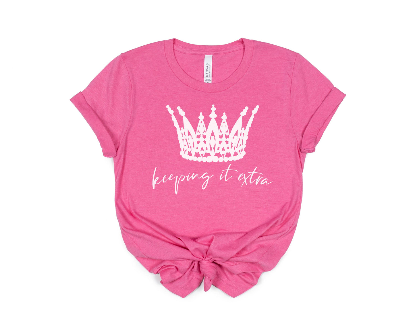 Keeping It Extra Charity Pink Tee White Ink with a white crown graphic and the phrase "keeping it extra" displayed. The t-shirt is knotted at the front and isolated on a white background.