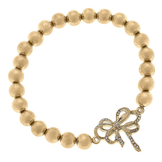 Gold beaded stretch bracelet with pavé bow charm in worn gold finish. Available in one size fits most.