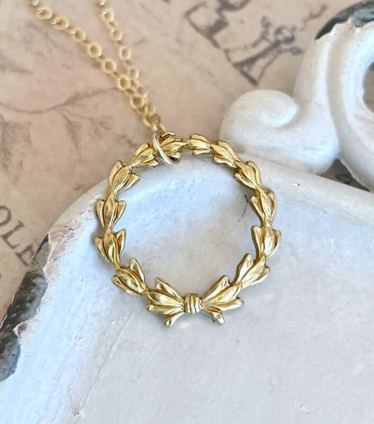 Delicate gold chain with laurel wreath pendant and small bow. Available in 16, 18, and 20 inch lengths.