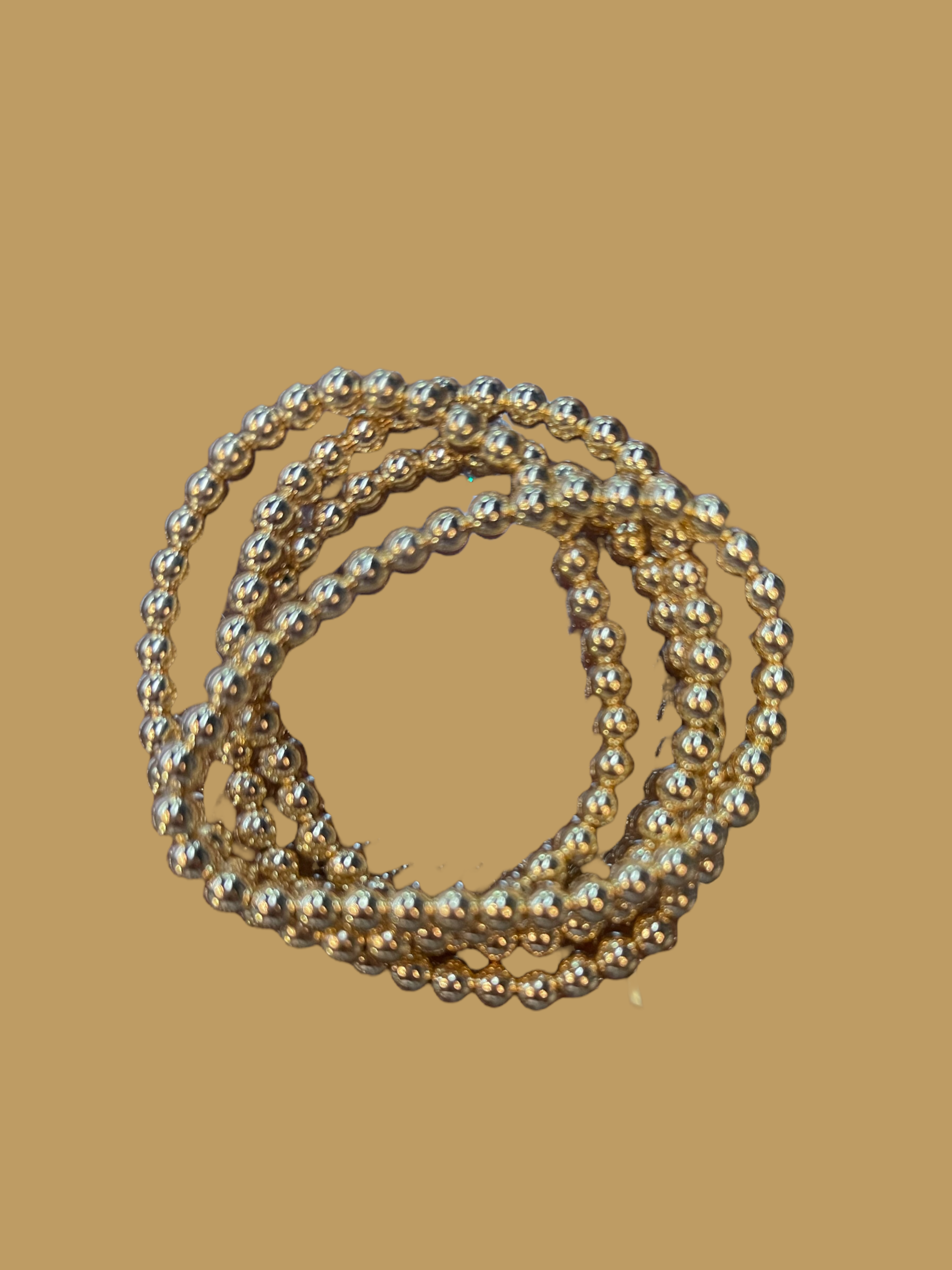 This product consists of a set of three 18 K Gold Filled Bead Bracelets. Each bracelet is composed of delicate beads, exquisitely crafted and intertwined to create a luxe, elegant look. The design sits comfortably on your wrist, radiating classic charm with every flicker. Available in one universal size to fit most wrists comfortably.