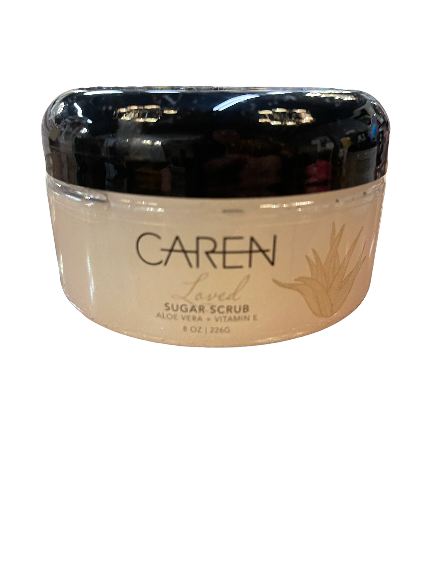 The product is Caren Loved Sugar Scrub which comes in a clear container with a black lid. The container is adorned with a white label that features gold text and leaf design.