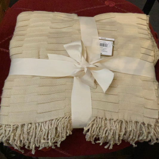 The Toulouse Throw Cream, 50 x 60 in., neatly folded, tied with a wide cream ribbon and price tag attached.