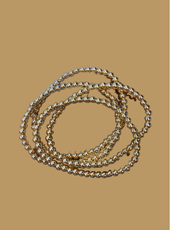 The product is an 18 K Gold Filled Bead Bracelet collection with shimmering accents. Available sizes for the bracelets are not specified.