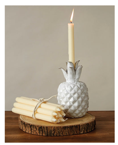 White pineapple-shaped candle holder with lit 10”H unscented taper candle. Candle available in 10” height.