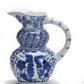 White ceramic pitchers with blue floral and geometric designs, curved handle; available in small sizes.