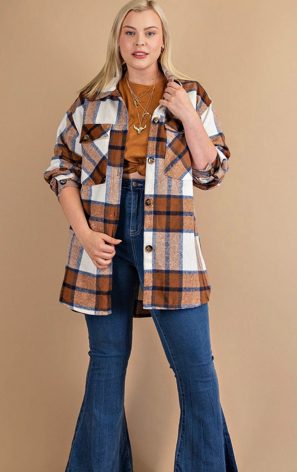 A woman with blonde hair wearing a **Brushed Plaid Button Down Shirt - PLUS** over a mocha mix brown top, paired with flared navy mix jeans, stands confidently in a neutral-toned studio setting.