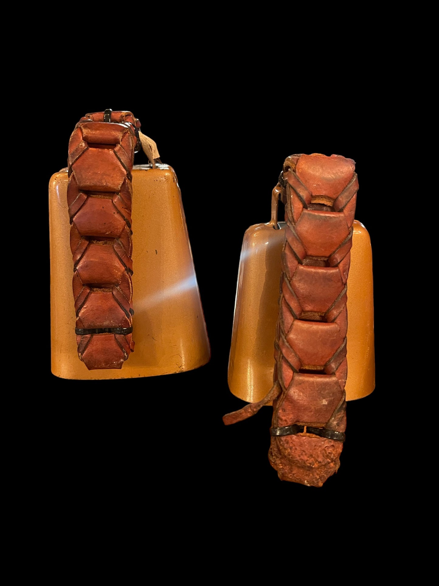 Two Antique Bells come with red leather straps braided around their handles. Each bell measures 5 inches. They showcase a classic, vintage aesthetic.