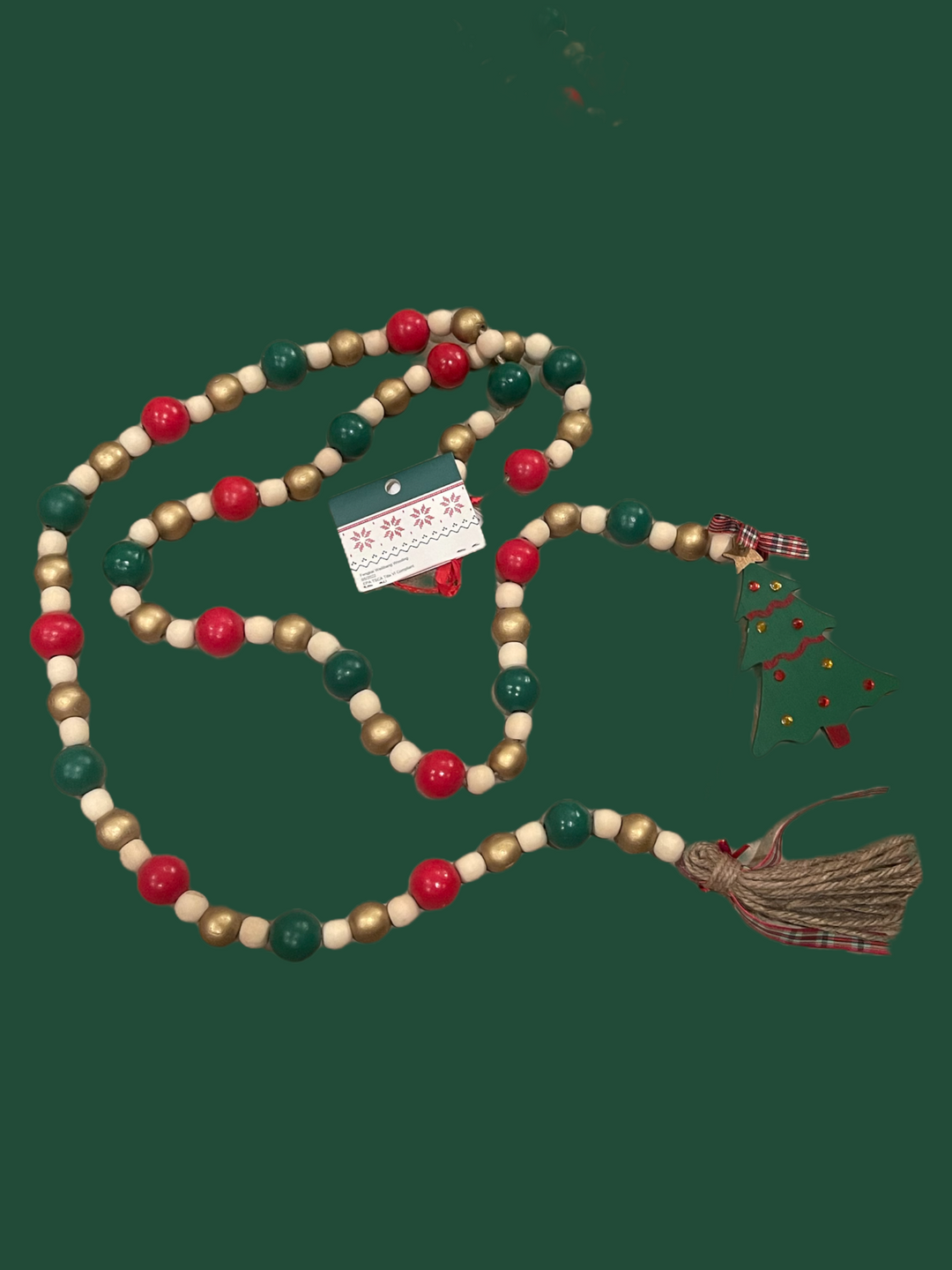 Christmas garland with red, green, and gold wooden beads, a wooden Christmas tree ornament, and a jute burlap tassel.