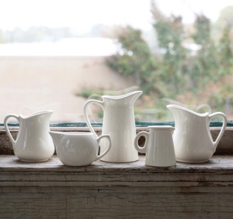 Set of five white creamers in assorted sizes. Sizes range from small to large. Only the creamers are shown.