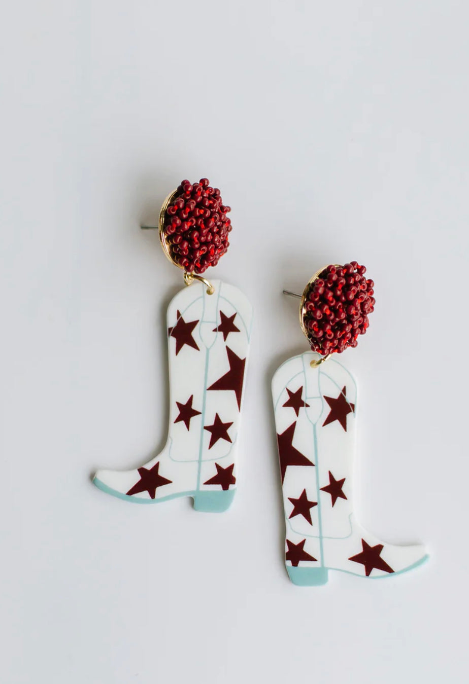 White cowboy boot-shaped dangle earrings with blue outlines, red stars, and red textured studs. Sizes: S, M, L.