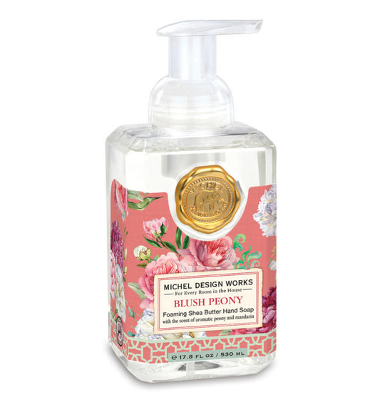 The product is a soap dispenser housing pink, foaming liquid. It is transparent and features a floral label with "Blush Peony Foaming Soap" written on it, complemented by an attractive gold seal.