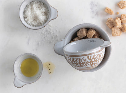 Set of 4 measuring cups with Was Relief Pattern; available in varying standard sizes.