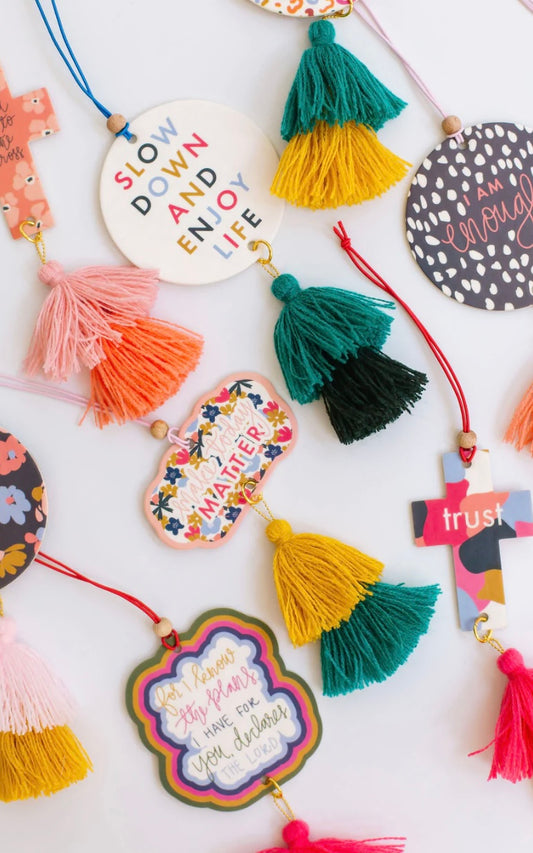 Handmade Air Fresheners in an array of colors and unique circular shapes. Each piece features inspirational quotes and floral patterns, decorated with vibrant tassels. Available in various sizes.