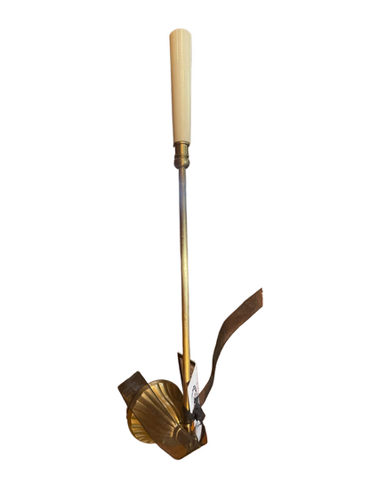 Brass candle snuffer with cream handle, long metal shaft, wide fan-shaped base, brown leather strap, and small tag. Sizes available.