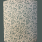 Cylindrical lampshade with beige fabric and green vine design, available in small, medium, and large sizes.