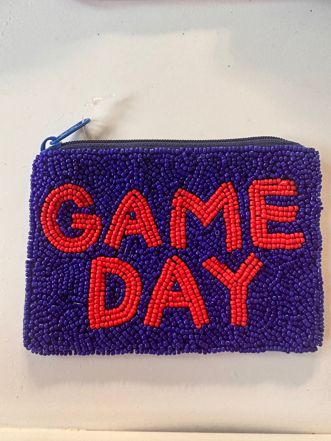 Rectangular blue sequin wallet with "GAME DAY" in red beads, top zipper closure. Available in one size.
