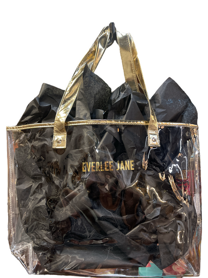 Clear tote bag with gold handles and trim, black tissue, "EVERLEE JANE" in gold. Stadium-approved. Sizes: S, M, L.
