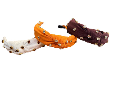 Three Krista fabric headbands in white, orange, and purple with gold and clear rhinestone studs. Sizes: S, M, L.