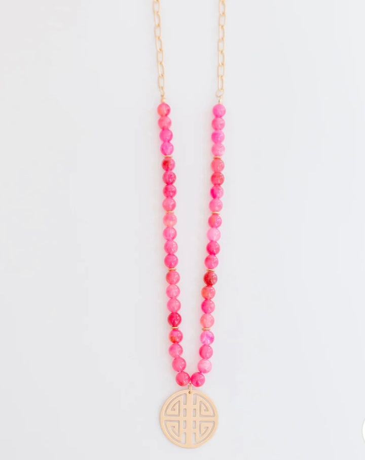 Bright pink beaded gold chain necklace with a round, cut-out design pendant. Available in various sizes.