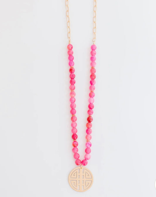 Bright pink beaded gold chain necklace with a round, cut-out design pendant. Available in various sizes.