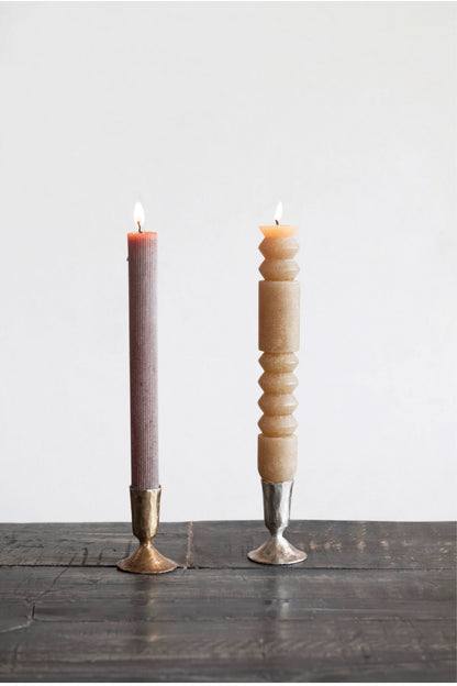 Tall mauve ribbed candle and beige geometrically-carved candle in metal taper holders. Available in 8", 10", and 12" sizes.