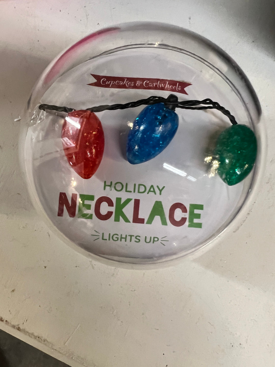 Holiday Light Up Necklace in a circular plastic container with red, blue, and green light-up bulb charms.