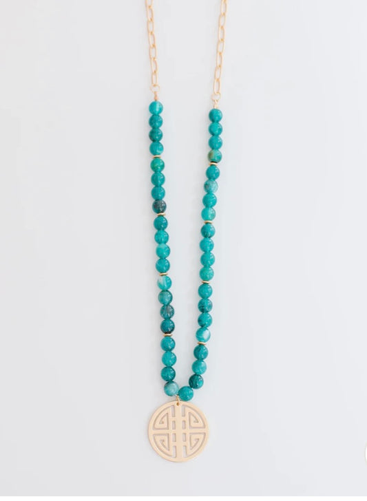 Michelle Mc Dowell Necklace with turquoise beads, gold chain, and round cut-out pendant. Available in multiple sizes.