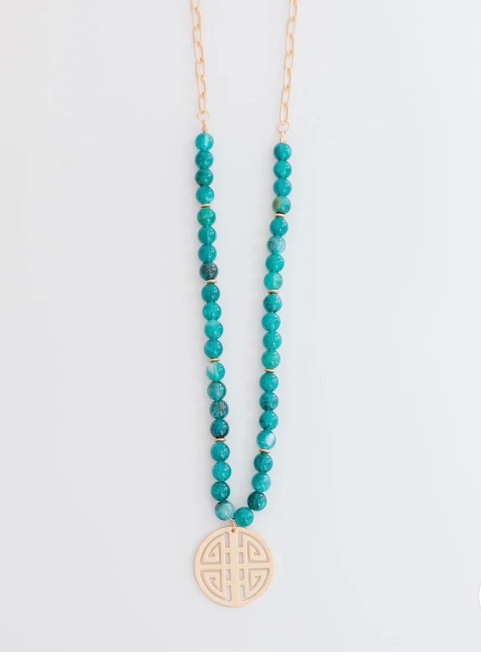 Michelle Mc Dowell Necklace with turquoise beads, gold chain, and round cut-out pendant. Available in multiple sizes.