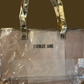 Clear tote bag with gold handles and trim, "EVERLEE JANE" on front. Stadium-approved. Sizes: Small, Medium, Large.