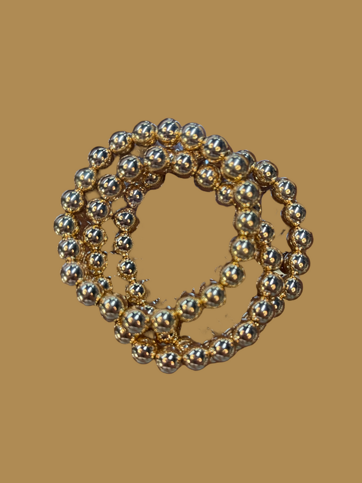 These 18 K Gold Filled Bead Bracelets are beautifully crafted, boasting a luxurious shine. The bracelets come as a set, elegantly looped together for added aesthetic appeal. Available sizes range from small to large to accommodate different wrist sizes. Each bead is meticulously designed, providing a polished and elegant finish that stands out. Its gold filling ensures both durability and long-lasting wear. An ideal purchase for those who appreciate fine jewelry pieces with an air of simplicity and